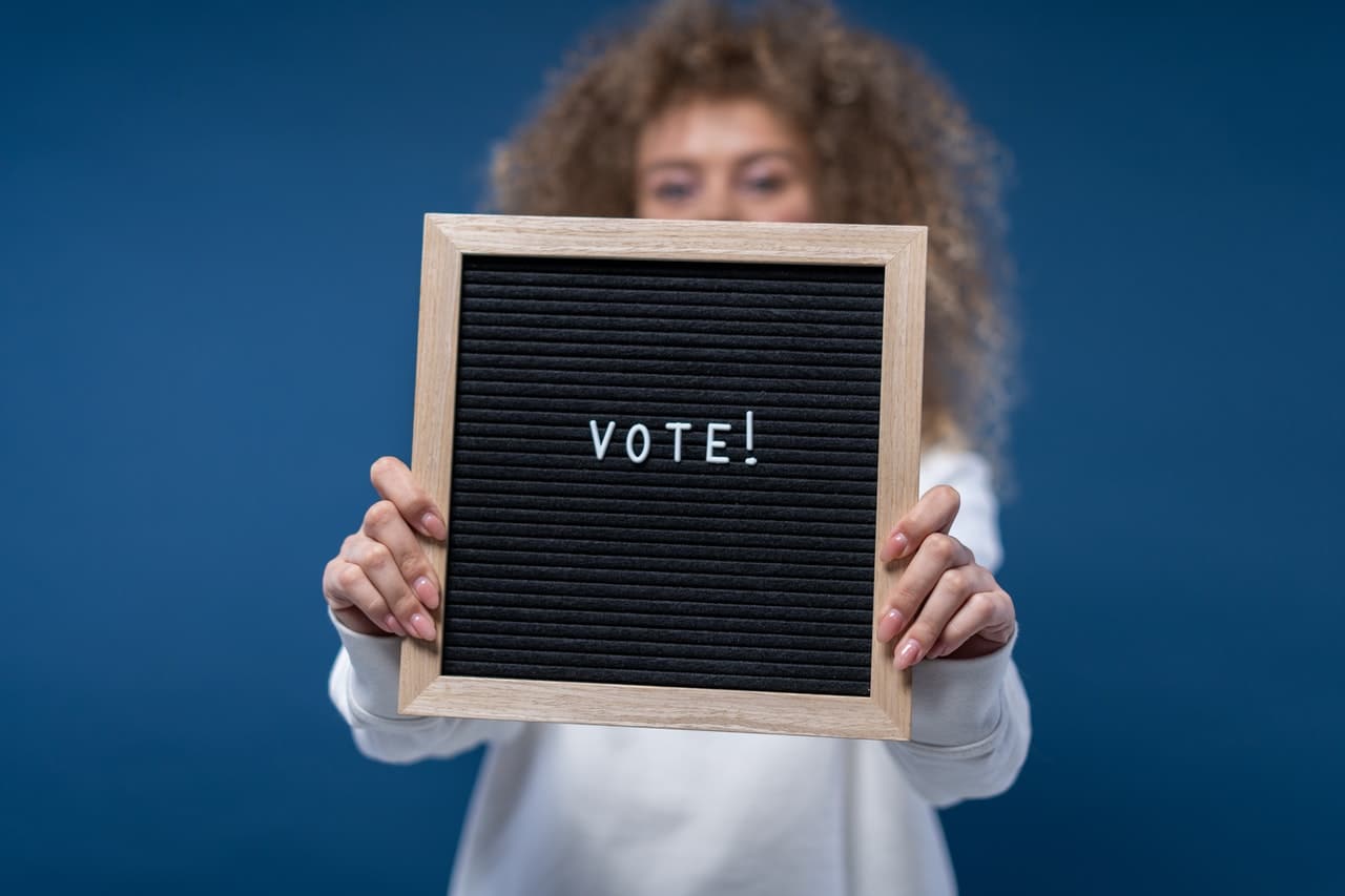 woman holding sign with vote on it