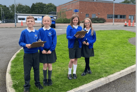 four schoolchildren hold clipboards