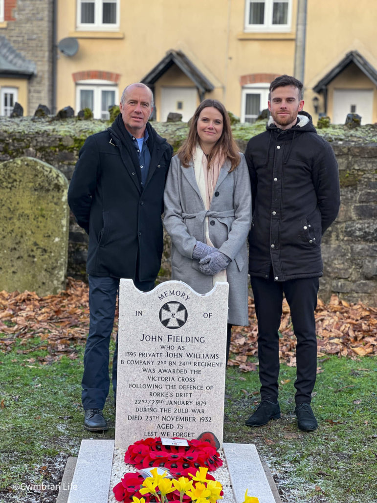 a dad and two of adult children stood by a grave