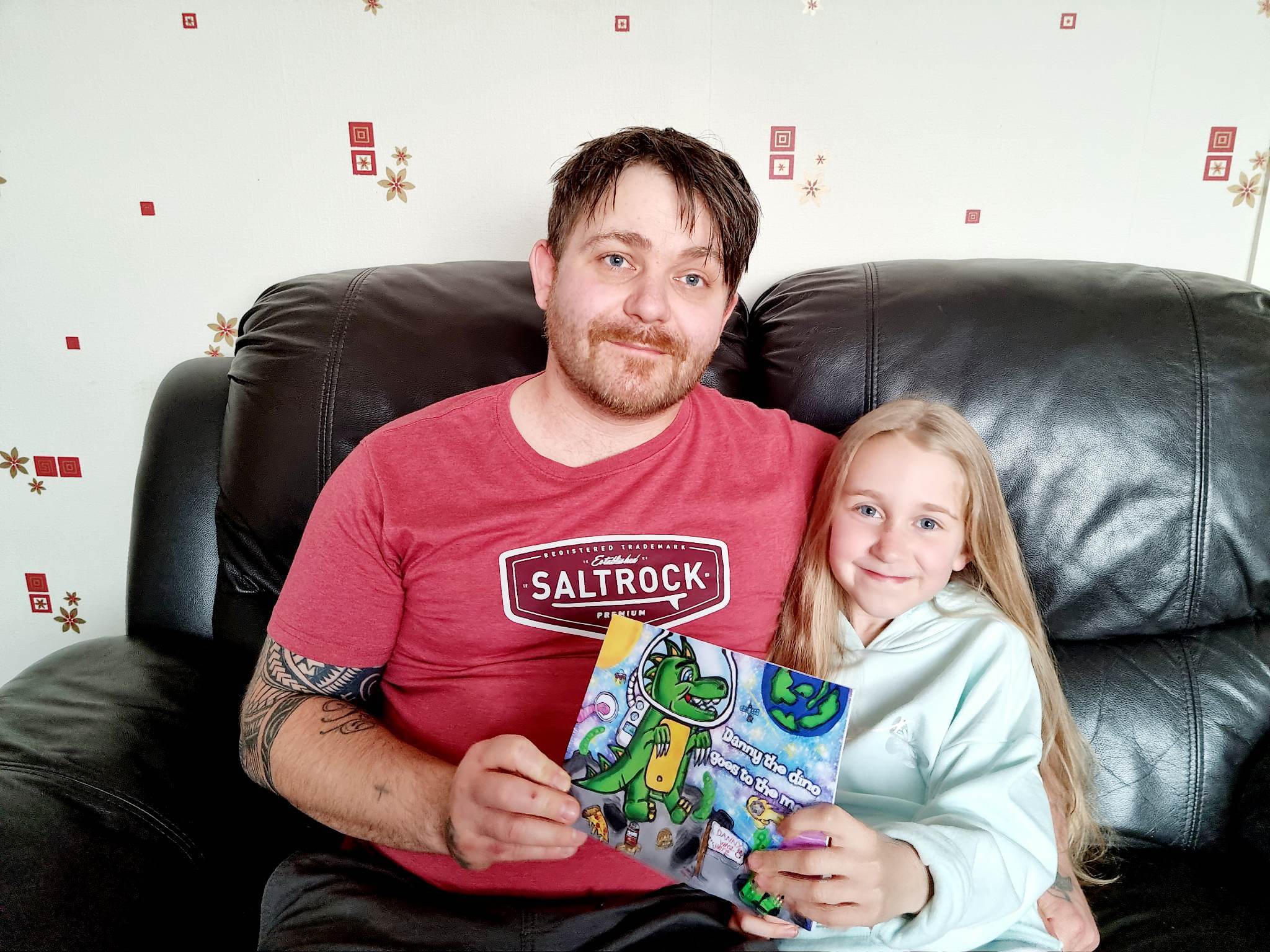a man and his daughter hold a children's book