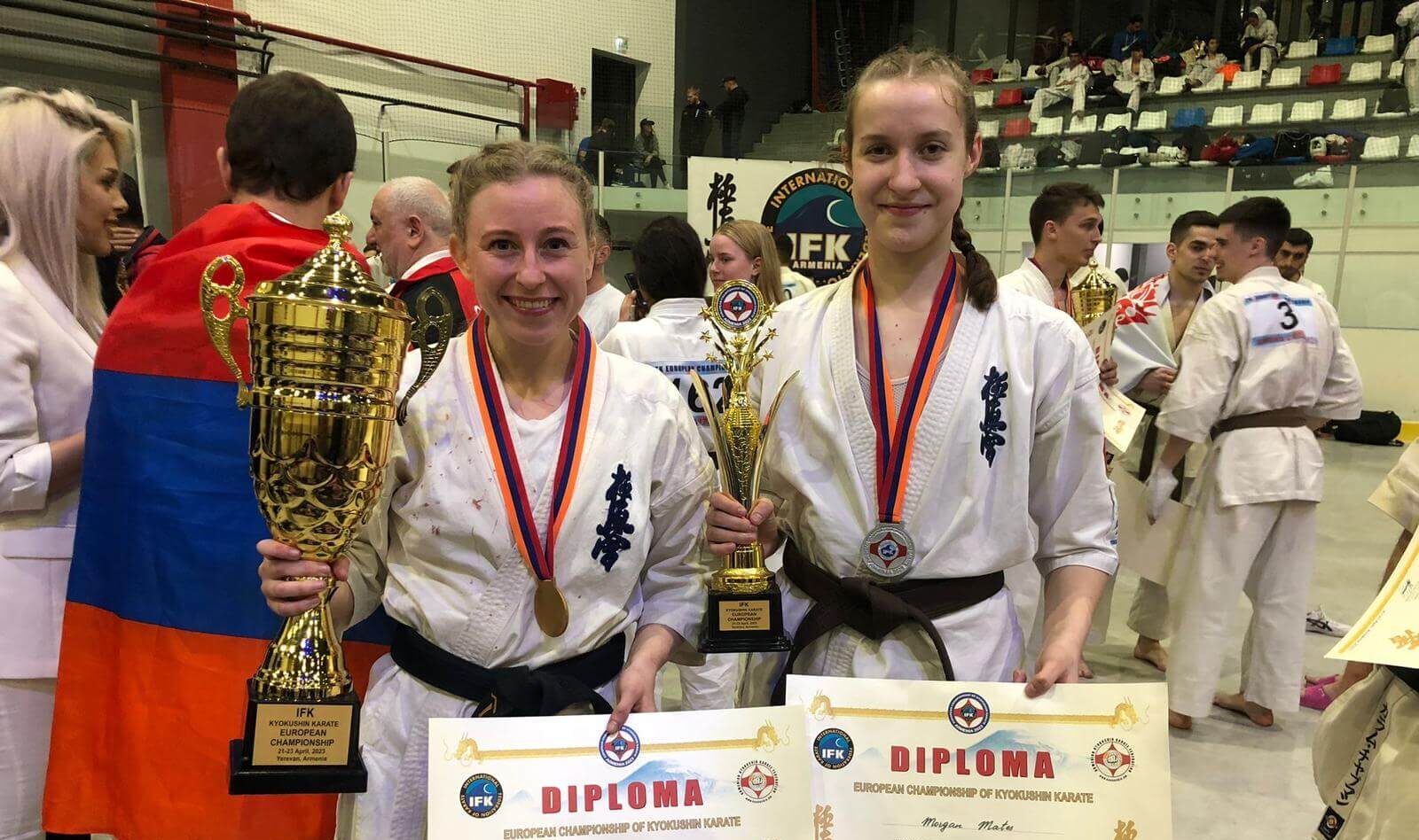 two women hold karate trophies after fighting