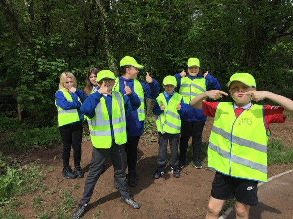 children in high viz jackets hold thumbs up and smile