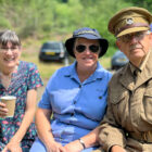two woman and man- two of them are dressed in military clothes at a reenactment event
