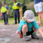 a child drawing in chalk on a pavement