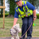 a police community support officer with a cockapoo dog