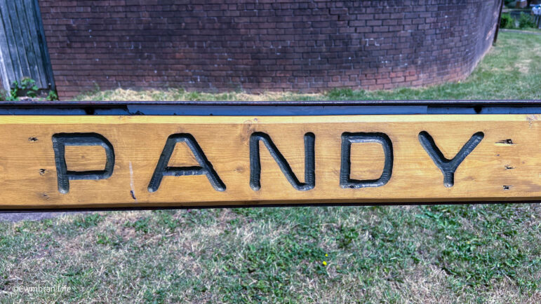 a wooden street sign saying Pandy