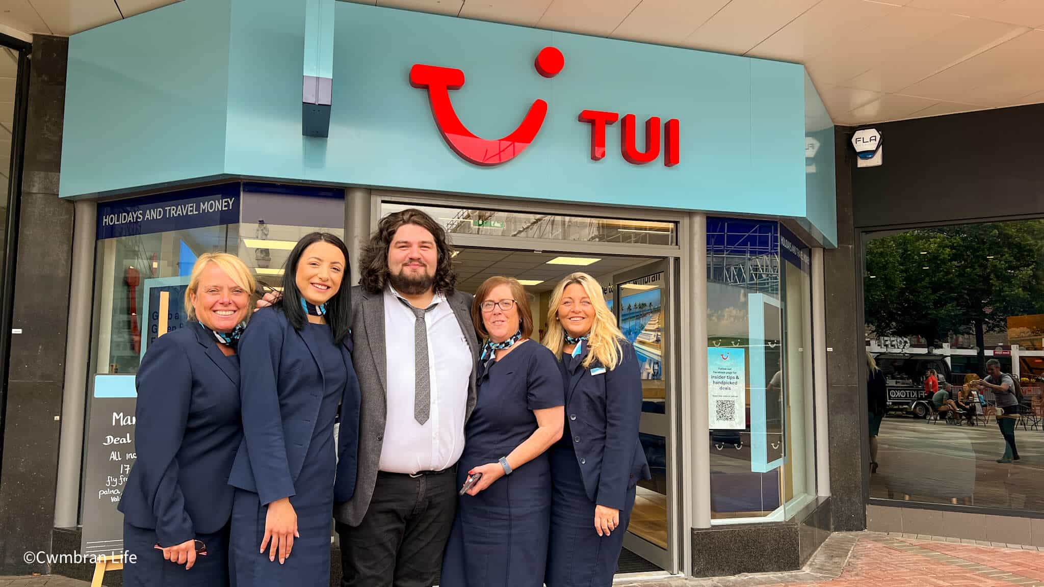 Singer Travis George with four staff outside their travel agent