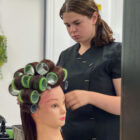 hairdressing student cuts hair on plastic model