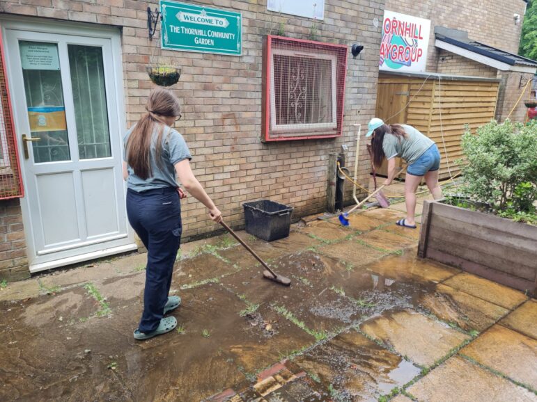 two women brushing patio slabs to clean them