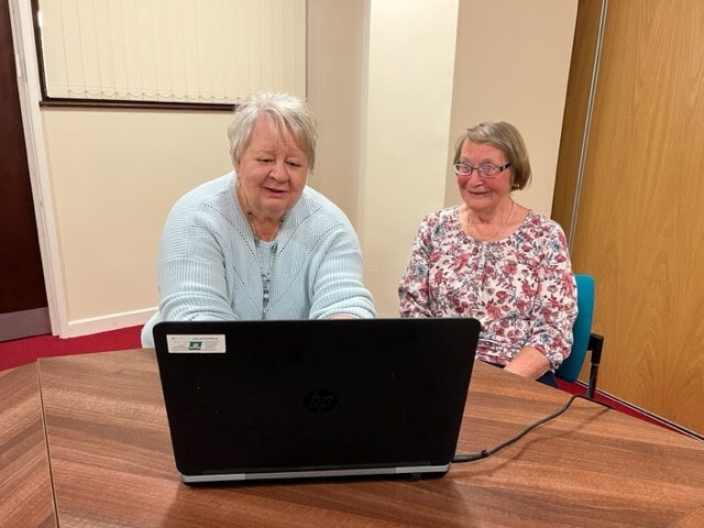 two women sat at a laptop