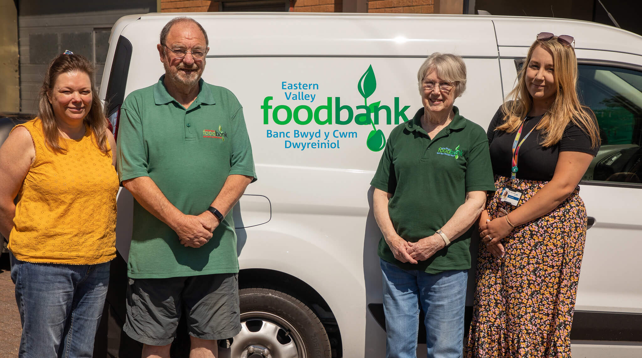 a group of four people stood by a food bank van