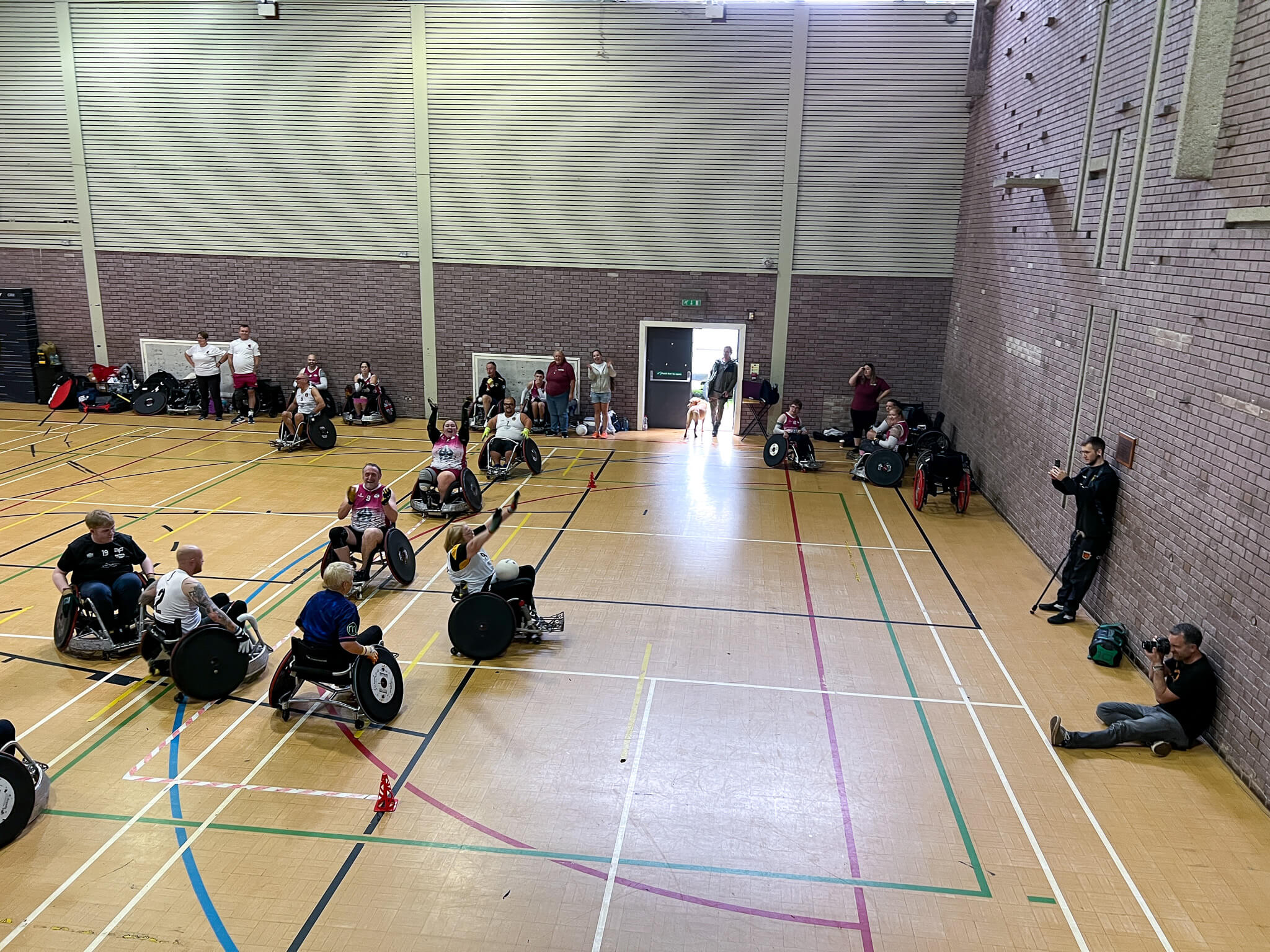 a female wheelchair rugby player raises her hands as she crosses the line to score