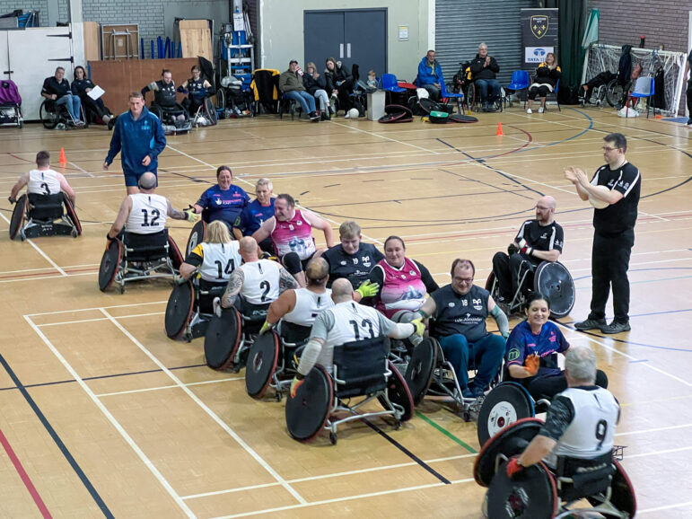 two rows of wheelchair rugby players shake hands after a match