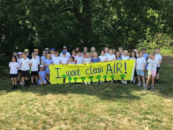 a large group of children hold a banner saying 'I want clean air'