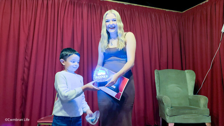 a boy presents a trophy to a woman