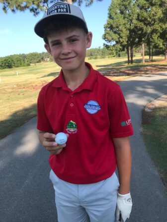 a teenage boy holds a golf ball