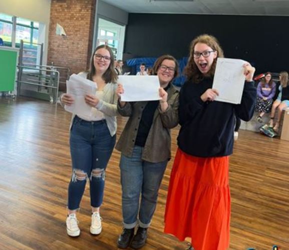 three pupils holding their exam results up