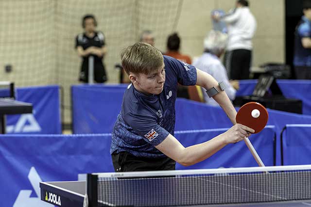 man playing table tennis with a crutch in left hand