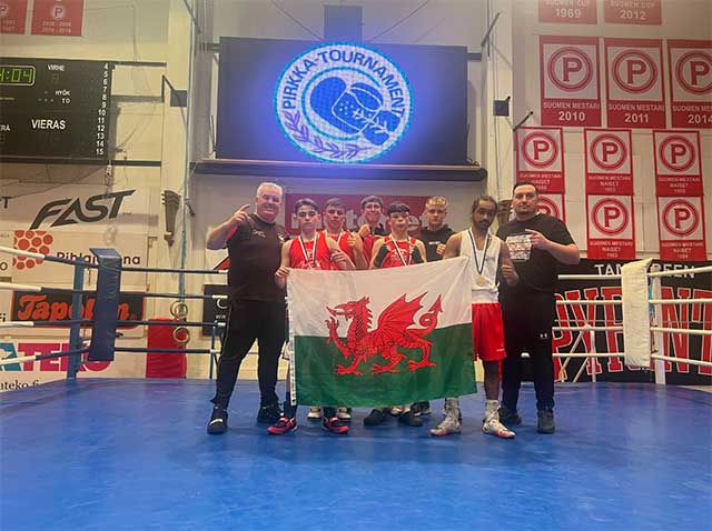 Boxers from the WABA East Division at the Prikka Box Cup in Finland- all stood in the boxing ring holding a wales flag