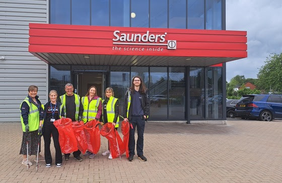 group of staff outside building hold litter picking kit
