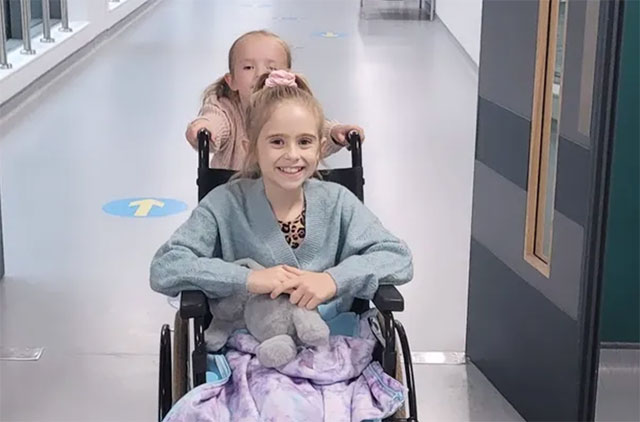 a girl pushes her older sister in a wheelchair