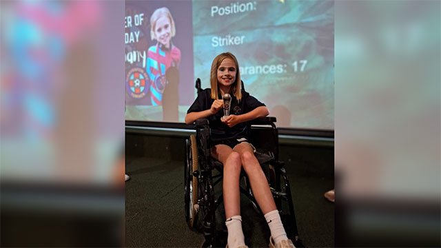 Bethany Lewis in her wheelchair holding a trophy