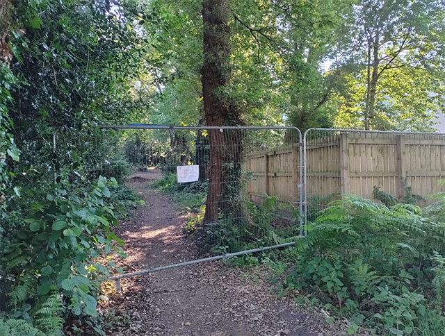 fencing blocking a path to a wood