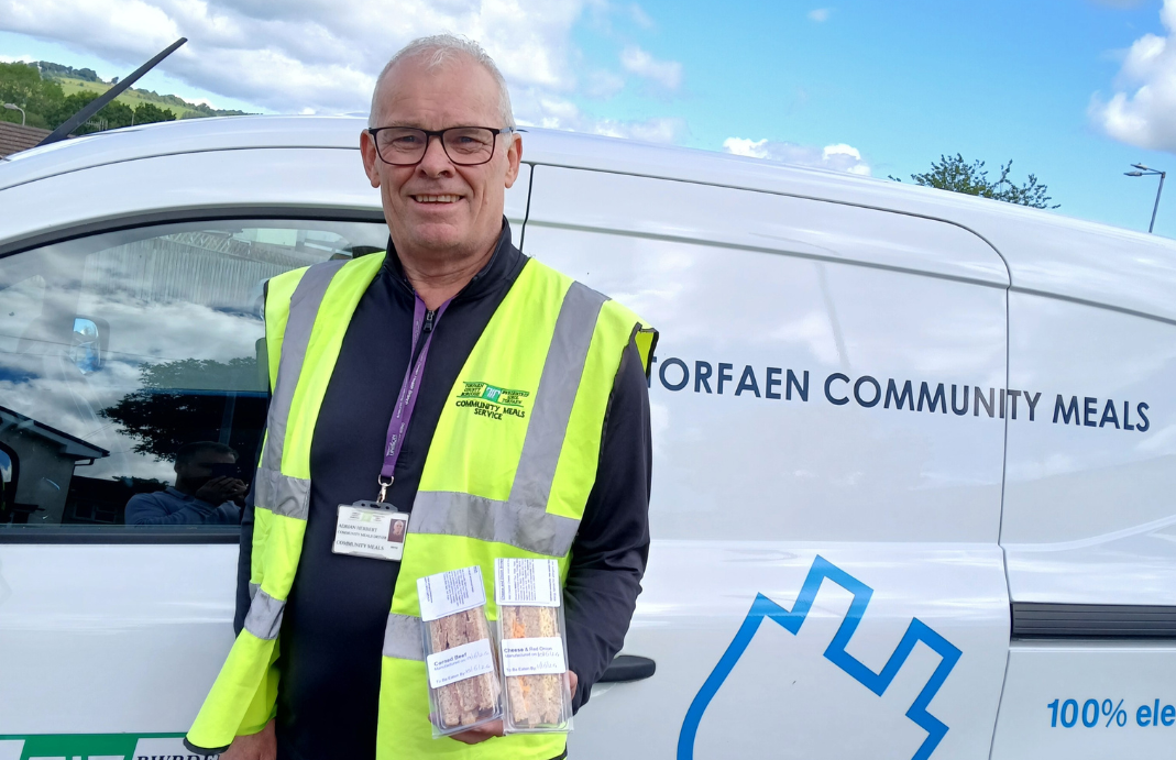 Adrian Herbert holds sandwichs stood by meals on wheels van