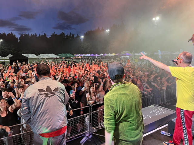 a band on stage sing to the large crowd