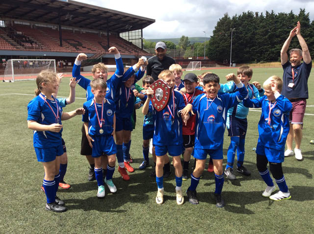 junior school football team celebrate with a trophy