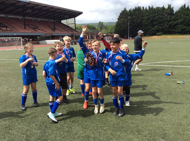 junior school football team celebrate with a trophy