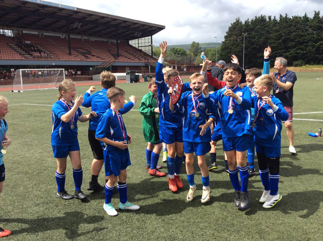 junior school football team celebrate with a trophy