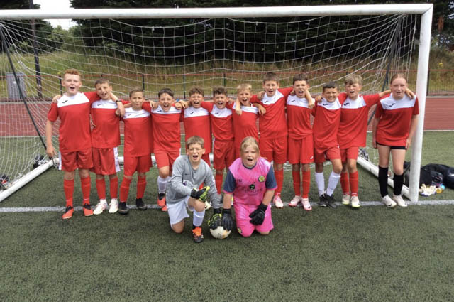 a junior school football team stood in the goals for a photo