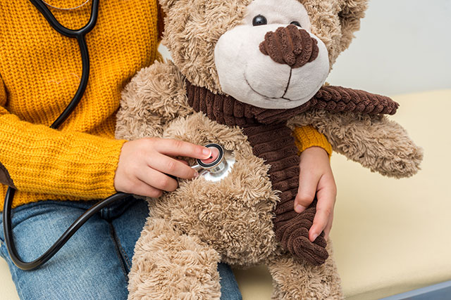 cropped shot of girl with stethoscope listening to teddy bear breath