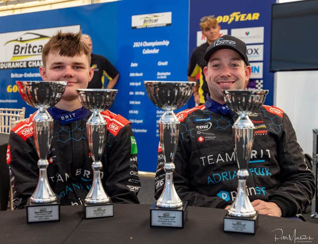 two teens with four trophies in front of them