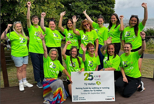 a group of people holding a large charity cheque and cheering