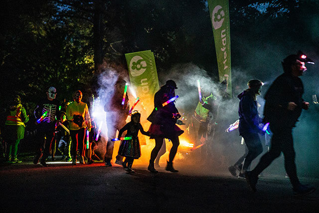 a group of people in halloween outfits run in dark woods