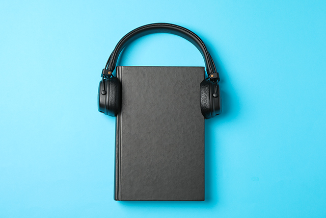 Closed book and headphones on blue background