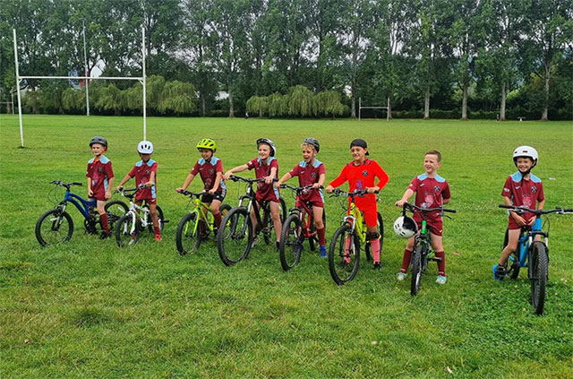 seven young cyclists smile for a photo on their bikes