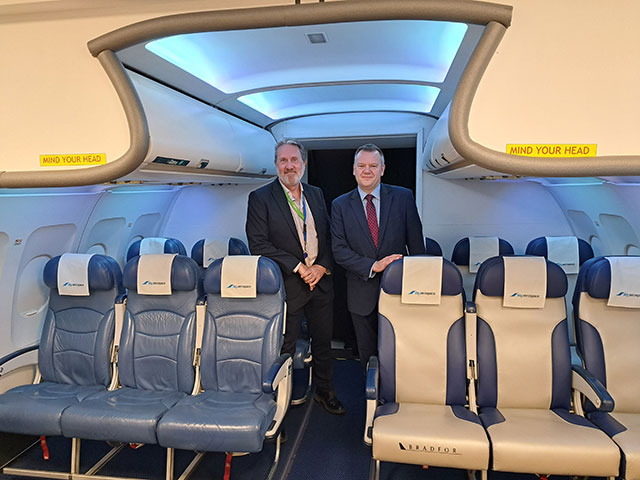 two men stood in plane cabin- it's actually a simulator, not a real plane