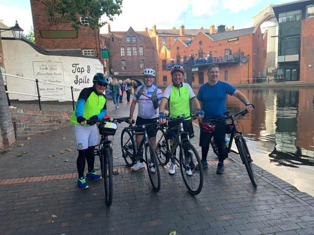 four men on bikes by a canal