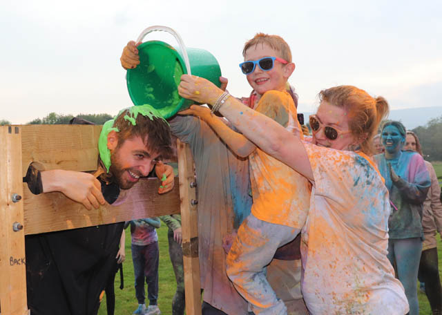 a boy and woman gunge a man in stocks