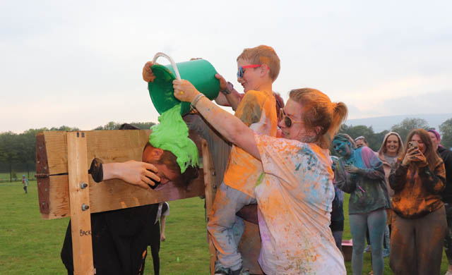 a boy and woman gunge a man in stocks