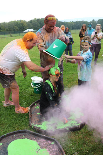 two men and boy pour gunge over a woman from a green bucket