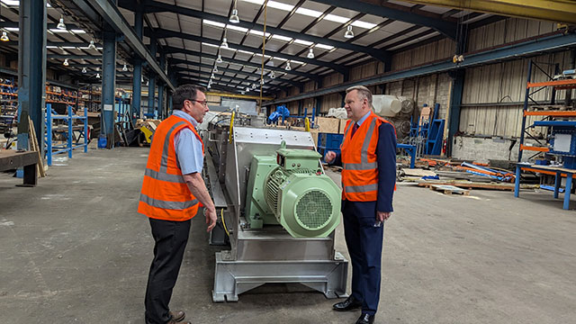 two men stood by machinery in a factory