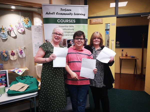 Three adult learners collect their GCSE results