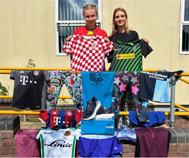 two women holding football shirts surrounded by second hand football kit