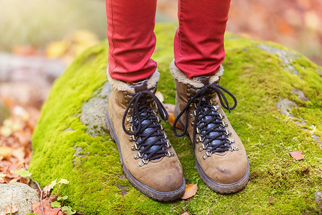 a person's legs and walking boots stood on a stone