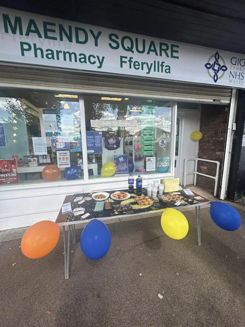 a pharmacy with a table of cakes outside it