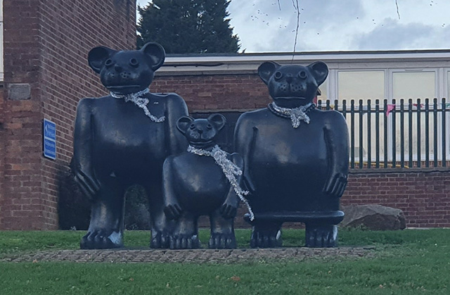 statues of three bears outside a school